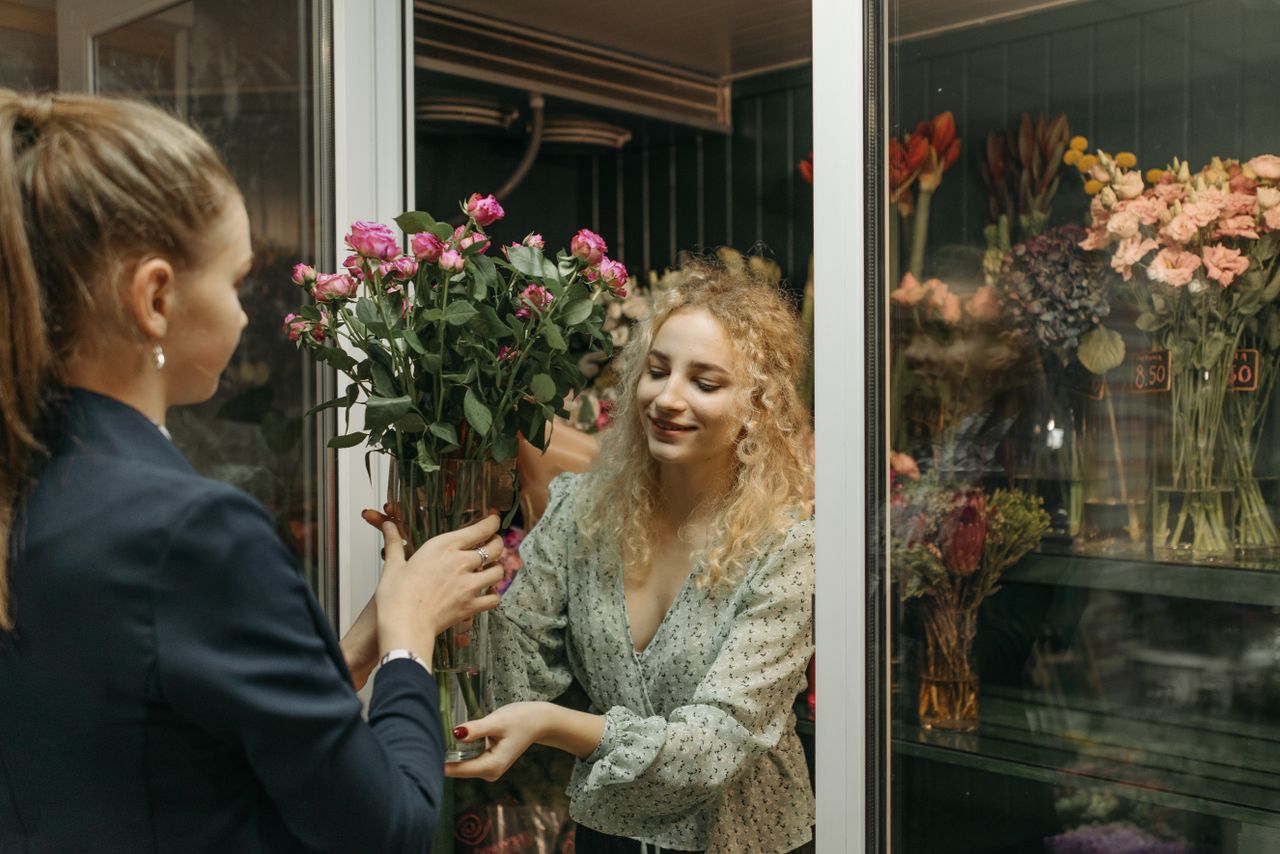 Two women exchanging a bouquet in a charming flower shop setting.